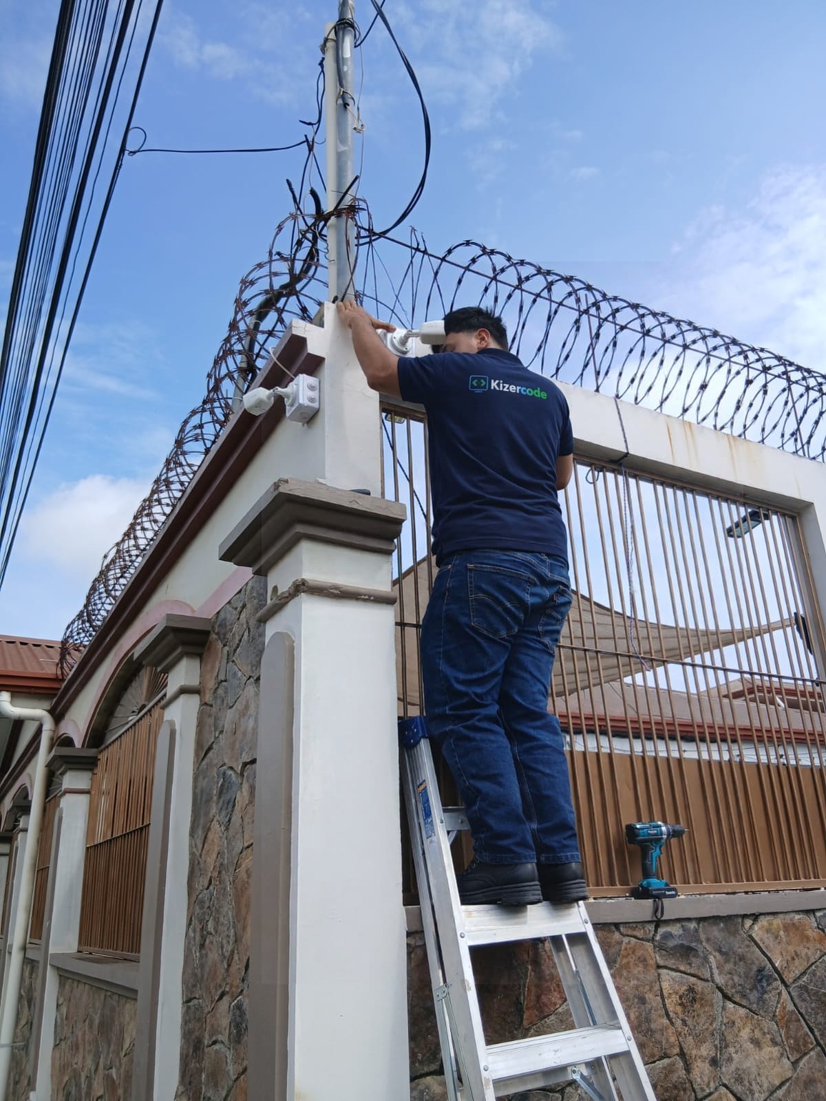 Técnico de Kizercode montando una cámara bala en el poste de un portón en El Progreso, Yoro